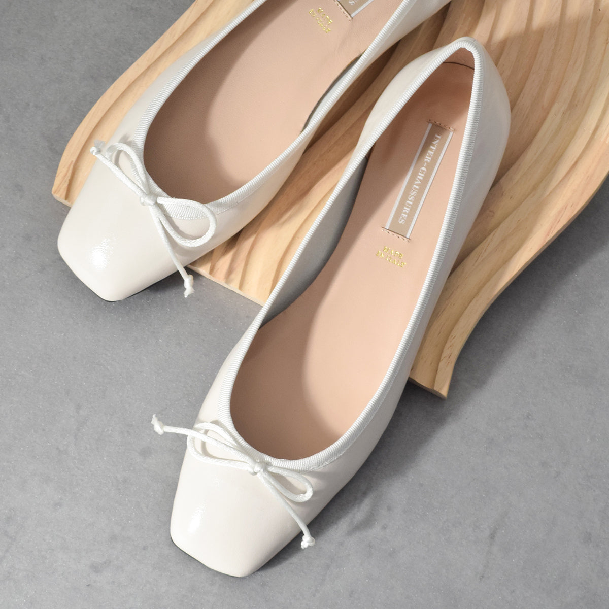 インターショシュール INTER-CHAUSSURES リボン付きスクエアフラットパンプス （アイボリーエナメル） アイボリーエナメル
